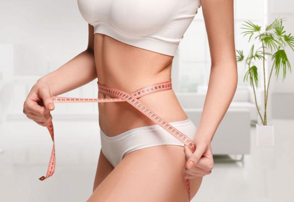 Woman with measuring tape around abdomen